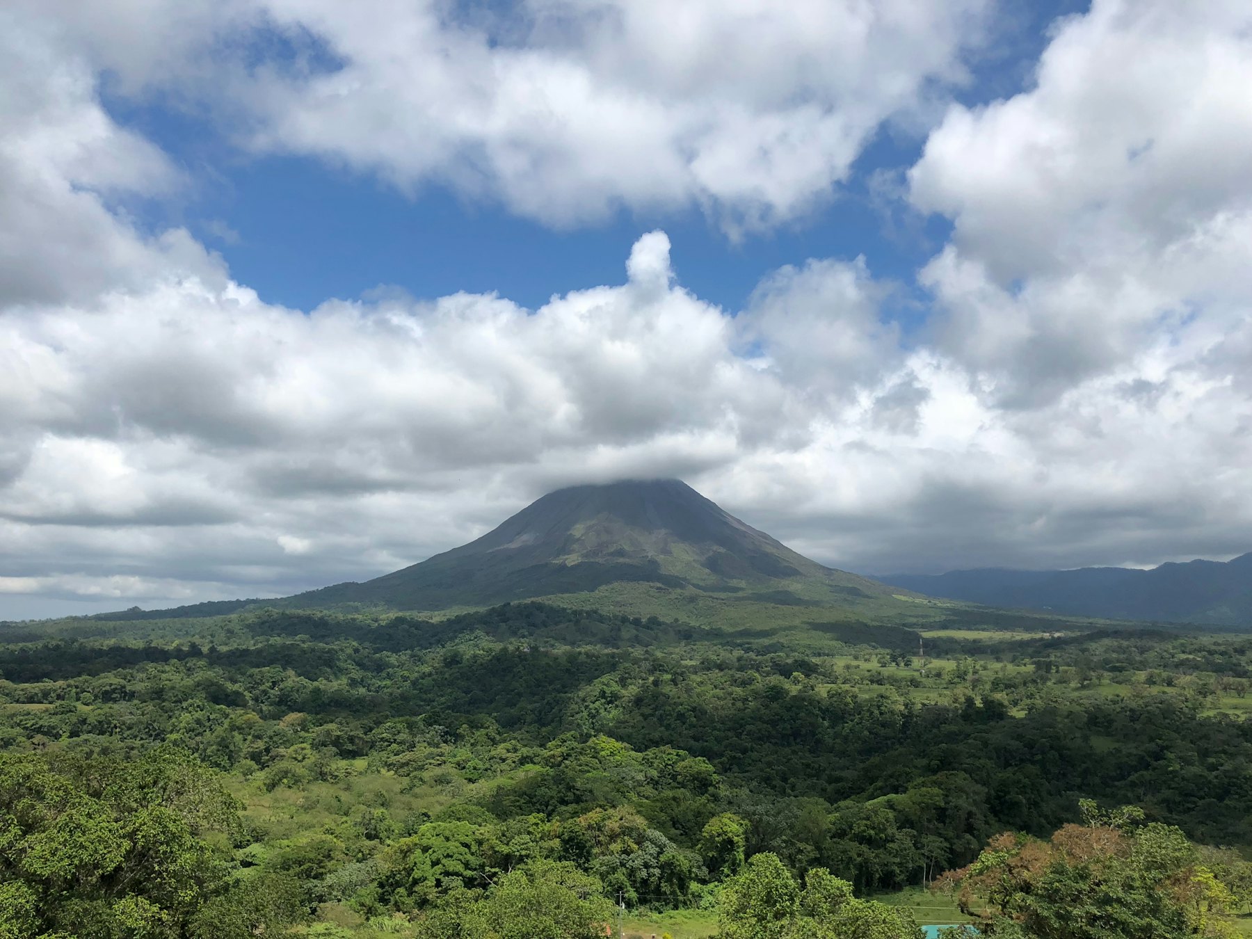 Volcán bajo las nubes sobre tierras bajas boscosas